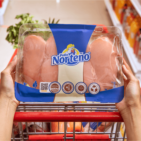 Manos de mujer en el carrito del supermercado con una bandeja de pechugas de Pollo Norteño.